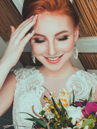 A bride smiling and touching her forehead.