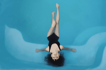 A woman sits in a bright blue pool