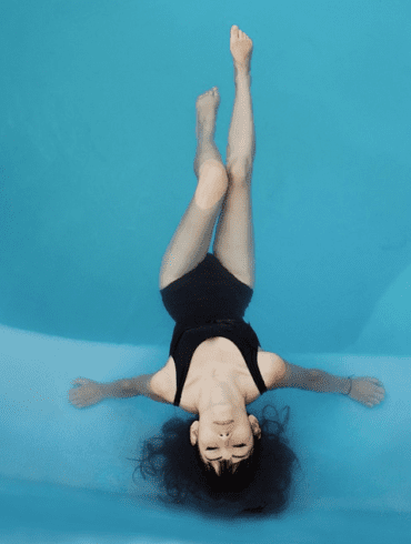 A woman sits in a bright blue pool