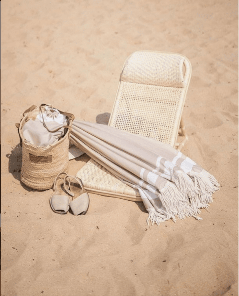 A beach chair and accessories sit in the sand