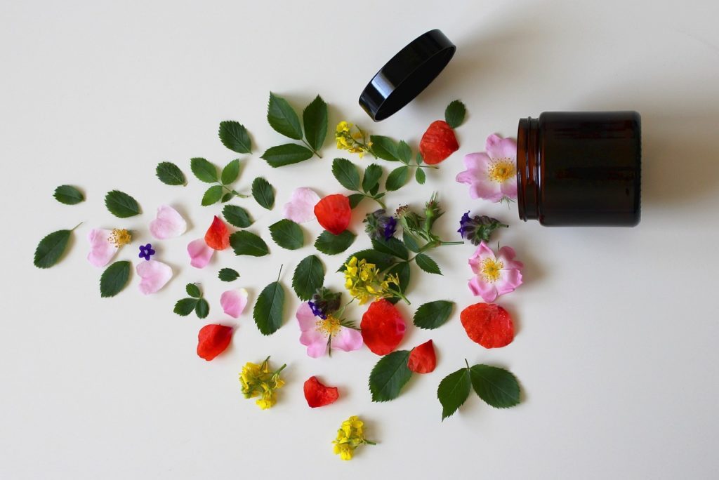 A jar filled with flowers and leaves on a white surface.