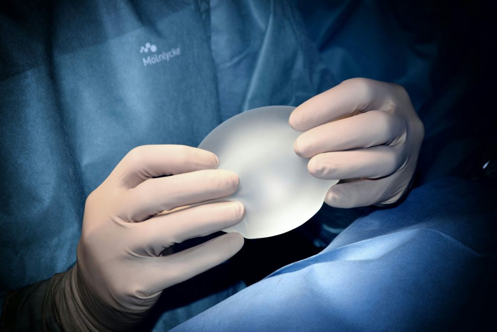 a doctor holding a silicone breast implant