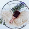 Hair extensions with a brush and flowers on glass table