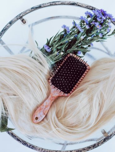 Hair extensions with a brush and flowers on glass table