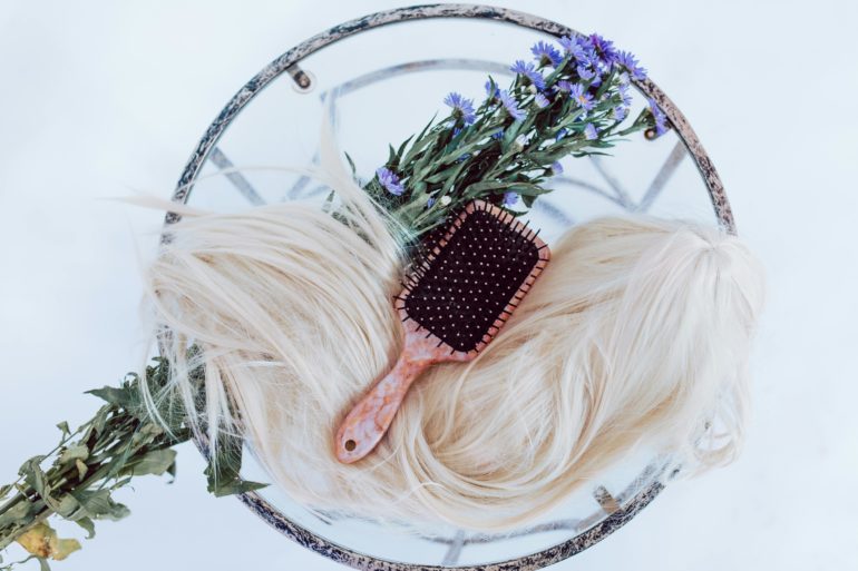 Hair extensions with a brush and flowers on glass table