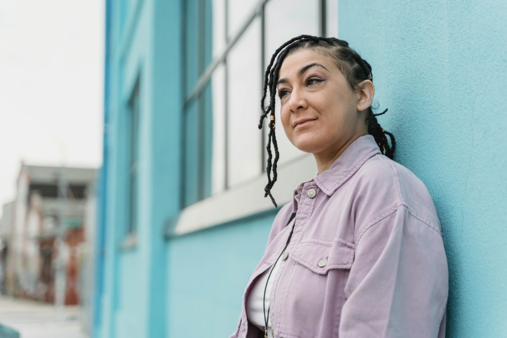 a woman with braided hair standing next to a blue building