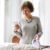 a beautiful woman looking at her phone while ironing